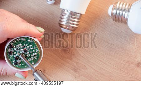 Woman Repairing A Led Lamp With A Soldering Iron