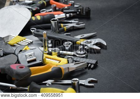 Handyman Tool Kit On Black Wooden Table. Many Wrenches And Screwdrivers, Pilers And Other Tools For 