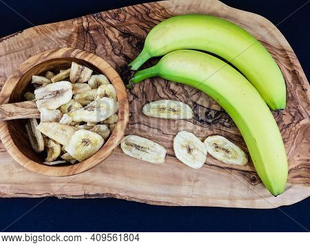 Some Dried Banana Chips On Olive Wood
