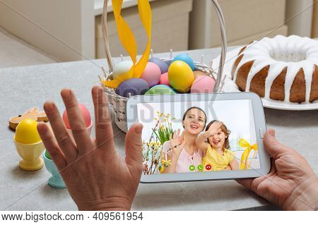 An Elderly Woman Holds A Digital Tablet And Yellow Eggin Her Arms And Talks To Her Granddaughters Vi