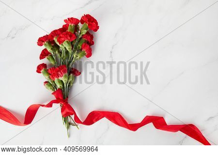 Beaytiful Carnation Flowers With Red Ribbon On Marble Background. Top View