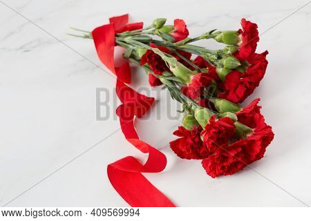 Beaytiful Carnation Flowers With Red Ribbon On Marble Background. Top View