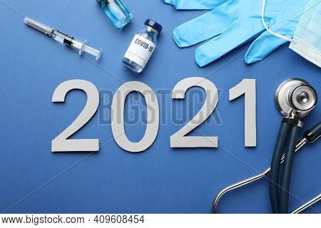 Flat Lay Composition With Coronavirus Vaccine And Number 2021 On Blue Background