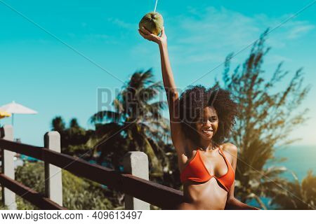 A Happy Drop-dead Gorgeous Young African-american Female In An Orange Swimsuit Is Leaning Against A 
