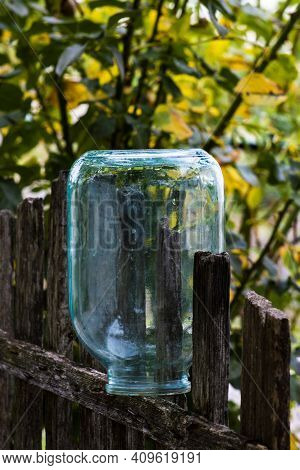 A Three-litre Glass Jar On A Wooden Fence. Front View On A Sunny Summer Day.