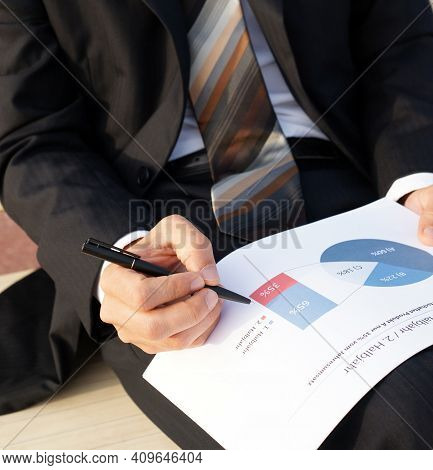 Businessman Evaluates Company Data And Checks Charts And Values
