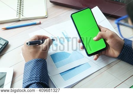 Rear View Of Man Hand Using Smart Phone On Office Desk