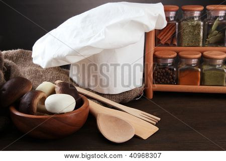 Sammansättning med kockens hatt och kitchenwear på bordet på grå bakgrund