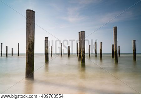 Long Exposure Seascape. Taken At The North Sea In Petten With The Pole Village In The Sea, Blue Sky,