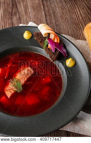 Ukrainian Traditional Borshch. Beetroot And Cabbage Soup With Meat. Close-up Of The Dish In Black Pl