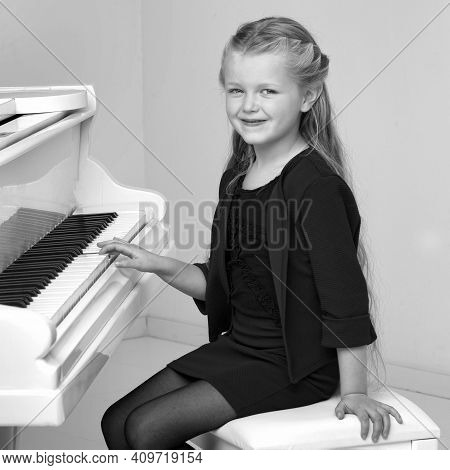 Beautiful Little Girl Playing On White Grand Piano. Black And White Shot Of Pretty Long Haired Girl 