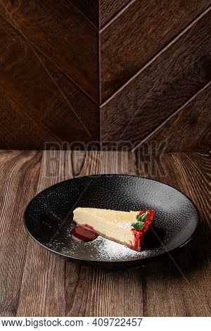 A Piece Of Cheesecake Served With Red Berry Sauce, Mint Leaf And Sugar Powder. Isolated Dish In A Bl