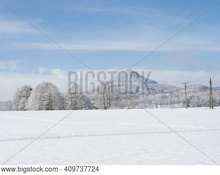Winter Landscape With Field, Frozen Trees And View Of Hill Or Mountain Klic In Luzicke Hory, Lusatia