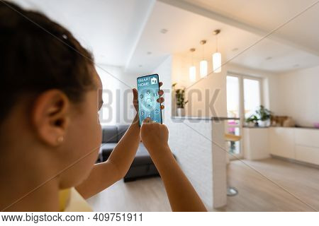 Shot Of Little Girl Using A Domotic System With Her Digital Tablet While Standing At Home.
