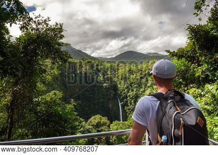 Tourist Looking At The La Fortuna Waterfall In Costa Rica. The Waterfall Is Located On The Arenal Ri