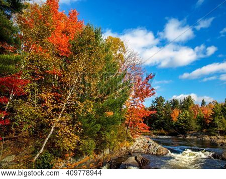 Bright Sky, Clouds, And Fall Foliage Add To The Flowing River, Chutes Prov Park, On, Canada