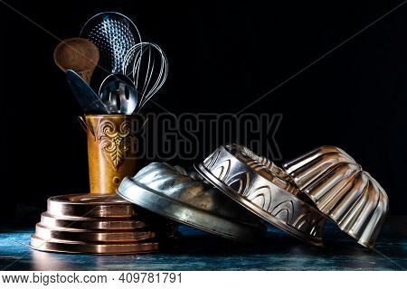 An Arrangement Of Vintage Bundt Cake Pans Against A Dark Background With A Vintage Tin Of Utensils I