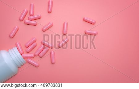 Pink Capsule Spread Out Of White Plastic Drug Bottle. Capsule And Pill Bottle On Pink Background. Vi