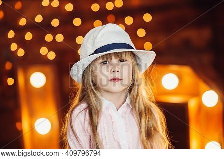 A Little Girl Looks Out From Behind The Wooden Letters Decorated With Lamps