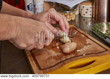 Woman Prepares Recipe At Home In The Kitchen. Cuts Mushrooms On Wooden Cutting Board