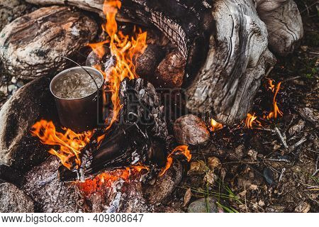 Kettle Stands On Fire. Cooking Food At Fire In Wild. Beautiful Big Log Burns In Bonfire Close-up. Su