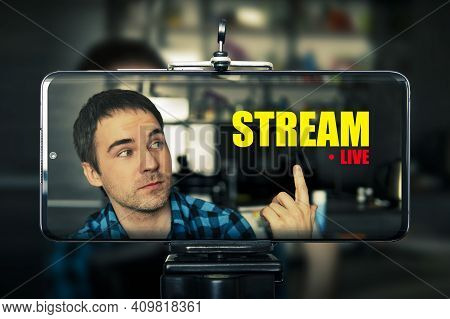 Live Streaming Mobile Concept: Hand Holding An Live Streaming At Home. Screen Graphics Are Made Up. 