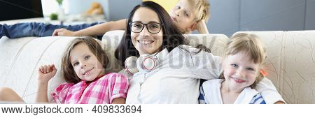 Woman Is Sitting On Sofa With Two Girls And A Boy Is Standing Next To Laptop. Teaching Children Onli