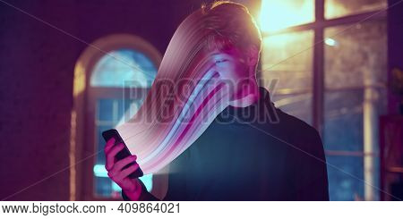 Cinematic Portrait Of Stylish Man In Neon Lighted Interior Using A Smartphone. The Face Is Smeared, 
