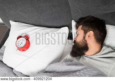 Man Bearded Hipster Sleepy Face In Bed With Alarm Clock. Problem With Early Morning Awakening. Get U