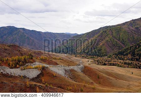The Mountain Road Serpentine Descends From The Cliff Into A Picturesque Autumn Valley.