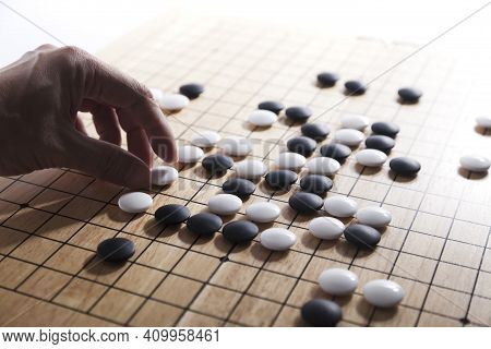 Player\'s Hand Put Stone On The Game Board - An Ancient Game Also Known As Baduk In Korean, Weiqi In