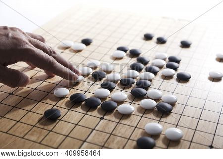 Player\'s Hand Put Stone On The Game Board - An Ancient Game Also Known As Baduk In Korean, Weiqi In