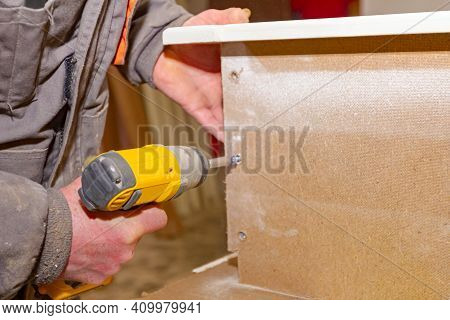 Worker In Carpentry Uses Professional Manual Power Tool, Acu Drill, And Twists The Screws On The Woo