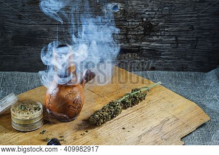 Old Brown Steamung Bong And Open Cannabis Grinder With Chopped Marijuana Weed And Medical Cannabis I