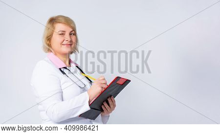 Banner- Long Format. An Attractive Senior Female Doctor In White Coat With Sthetoscope, Writes Analy