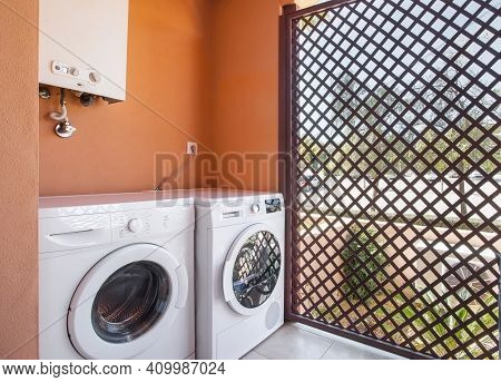 Simple Laundry Room With A Machine For Washing And Drying, A Boiler On Top And A Fenced Off Division