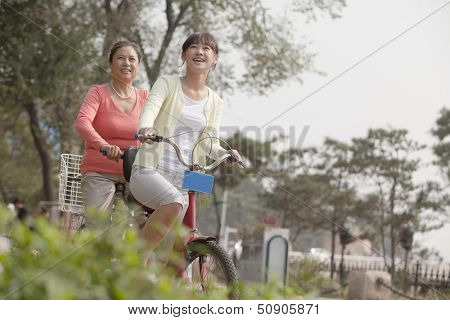 Grandmother and granddaughter riding tandem bicycle, Beijing