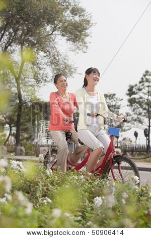 Grandmother and granddaughter riding tandem bicycle, Beijing