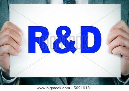 businessman wearing a suit holding a signboard with the term RnD, research and development, written in it