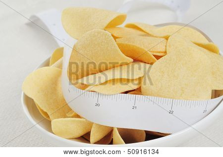 closeup of a bowl with low fat potato chips and a measuring tape 