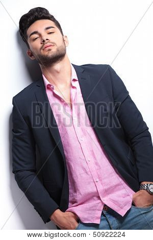 young fashion man leaning back while holding his hands in his pockets and looking into the camera. on a white background