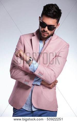 young casual man looking at his watch. on gray background