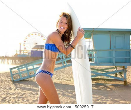 Beautiful surfer teen girl with surfboard in Santa Monica beach California Lifeguard house