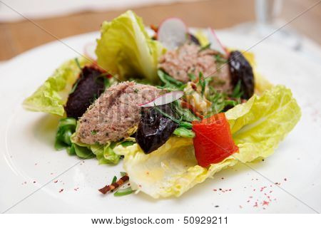 Creative salad with prunes and fish paste on plate, close-up