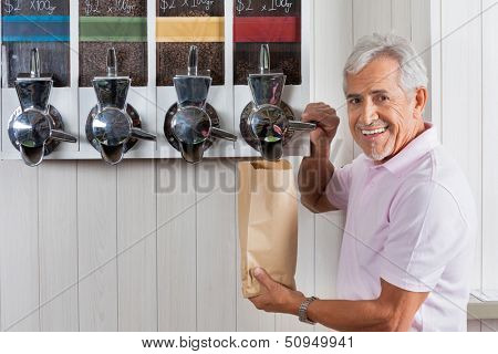 Portrait of senior man buying coffee beans from vending machine at grocery store
