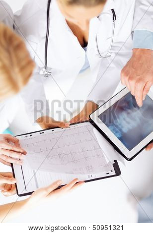 healthcare, hospital and medical concept - group of doctors looking at x-ray on tablet pc