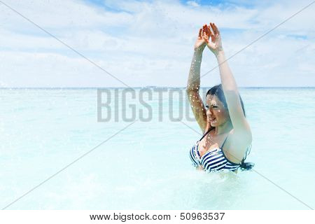 Cheerful pretty young woman splashin in sea