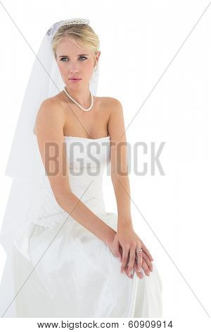 Thoughtful bride in off shoulder dress sitting against white background