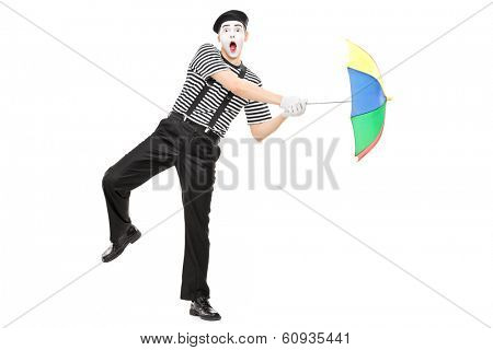 Full length portrait of a mime artist holding an umbrella simulating being blown by wind isolated on white background shot with tilt and shift lens
