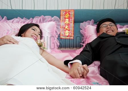 Bride And Groom Hold Their Hand And Lay On The Bed As Chinese Traditional